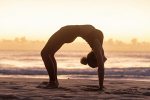 Mulher fazendo yoga na praia